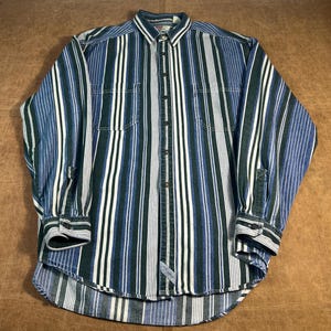May include: A long-sleeved button-down shirt with vertical stripes in shades of blue, green, and white. The shirt has two chest pockets and buttoned cuffs. The collar is a solid blue color.