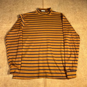 May include: Mustard yellow and navy blue striped long-sleeved top with a mock turtleneck. The shirt features a classic horizontal stripe pattern and is made of a soft, comfortable material. The sleeves have cuffs.