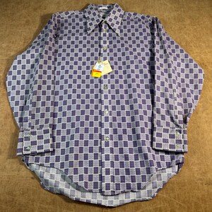 Può includere: Una camicia a maniche lunghe con bottoni caratterizzata da un motivo a scacchi viola e bianco con un design a griglia. La camicia presenta un colletto a punta, un'abbottonatura frontale e polsini con bottoni. Un'etichetta gialla e bianca.