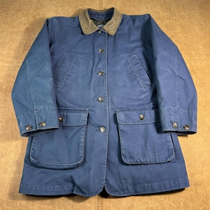 Puede incluir: Chaqueta azul con cuello marrón y cuatro bolsillos delanteros. La chaqueta tiene cierre de botones y botones en los puños. La chaqueta está hecha de un material duradero.