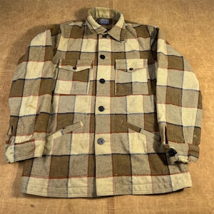 May include: A vintage plaid jacket in shades of tan, brown, and cream. The jacket features a button-down front, two chest pockets, and two side pockets. The fabric has a textured appearance, and the jacket has a classic, timeless design.