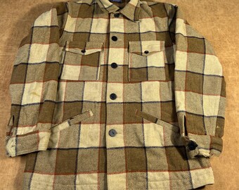 May include: A vintage plaid jacket in shades of tan, brown, and cream. The jacket features a button-down front, two chest pockets, and two side pockets. The fabric has a textured appearance, and the jacket has a classic, timeless design.