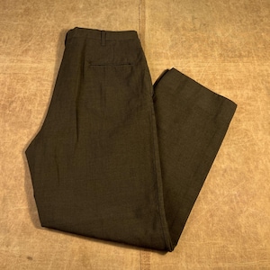 May include: Dark olive-green trousers with a classic design. The pants feature a button and zipper closure, belt loops, and pockets. The fabric appears to be a woven material, suitable for a variety of occasions.
