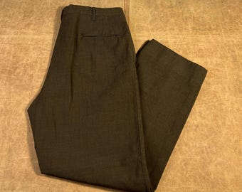 May include: Dark olive-green trousers with a classic design. The pants feature a button and zipper closure, belt loops, and pockets. The fabric appears to be a woven material, suitable for a variety of occasions.