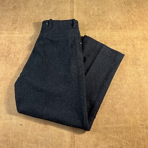 May include: Dark charcoal-colored trousers with a classic design. The pants are made of a textured fabric and feature a button and zipper closure. The trousers are folded neatly, showcasing the tailored fit and style.