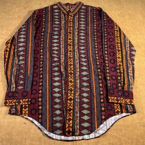 May include: A long-sleeved button-down shirt with a vibrant geometric design. The shirt displays vertical stripes in burgundy, grey, orange, and black, with diamond and gear-like shapes. The cuffs and collar have a contrasting pattern.