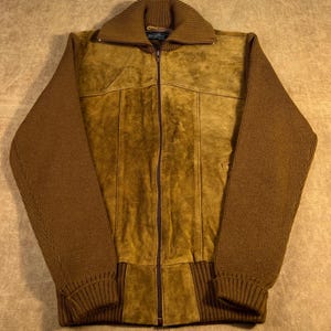 May include: A brown suede jacket with a knit collar and sleeves. The jacket has a full zipper closure and vertical seams down the front. The sleeves and collar are a darker shade of brown than the body of the jacket.