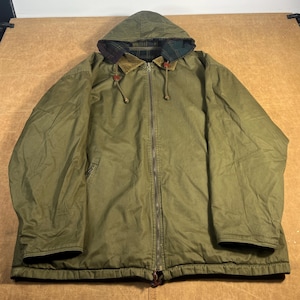 May include: Olive green hooded jacket with a full-length zipper. The jacket features a corduroy collar, a plaid lining in the hood, and a drawstring. The jacket has two front pockets and a drawstring at the bottom. The jacket is made of a durable, water-resistant material.