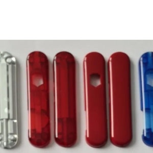 Puede incluir: Una colección de multiherramientas en varios colores. Las herramientas incluyen opciones plateadas, rojas y azules. Algunas herramientas tienen una abertura hexagonal, mientras que otras son sólidas. Las herramientas están dispuestas en una fila sobre un fondo blanco.