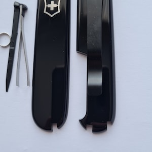 Cuchillo Victorinox original modificado a medida de 91 mm con escalas Plus, clip, pinzas negras, palillo negro, anilla partida y colgante.