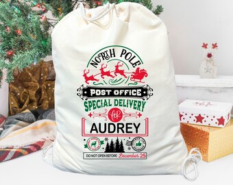 May include: A white canvas Santa sack with a red and green design that says "North Pole Post Office Special Delivery for Audrey" and "Do Not Open Before December 25".