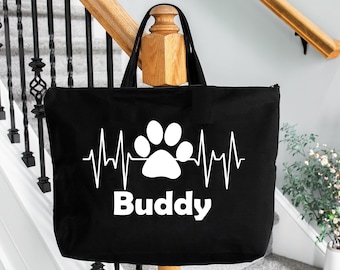 May include: Black canvas tote bag featuring a white paw print and heartbeat graphic. The text "Buddy" is printed below the graphic.