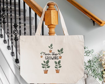 May include: Cream-colored tote bag with the text "Never Stop GROWING" and illustrations of potted plants. The bag has long handles and is made of a natural fabric. The design features green plants in brown pots.