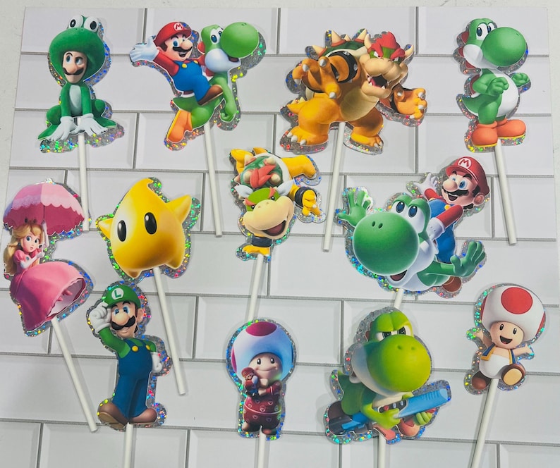 以下が含まれることがあります： マリオ、ルイージ、ピーチ姫、ヨッシー、クッパ、クッパJr.、キノピオ、黄色いルマなど、様々なスーパーマリオのキャラクターが描かれた12個のデコレーション用ケーキトッパー。それぞれホログラムの縁取りが施され、白いスティックに取り付けられています。