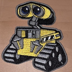 Könnte beinhalten: Gestickter Aufnäher mit der Figur Wall-E aus dem Animationsfilm. Der Aufnäher hat ein gelbes und graues Farbschema mit schwarzen Akzenten. Die Augen des Roboters sind blau. Der Aufnäher ist zum Aufbügeln oder Aufnähen auf Stoff gedacht.