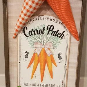 May include: Wooden framed sign with a rustic design. The sign features a "Carrot Patch" graphic with orange carrots, a bow, and the text "Egg Hunt & Fresh Product Open Daily." Two fabric carrots with green tops are attached.