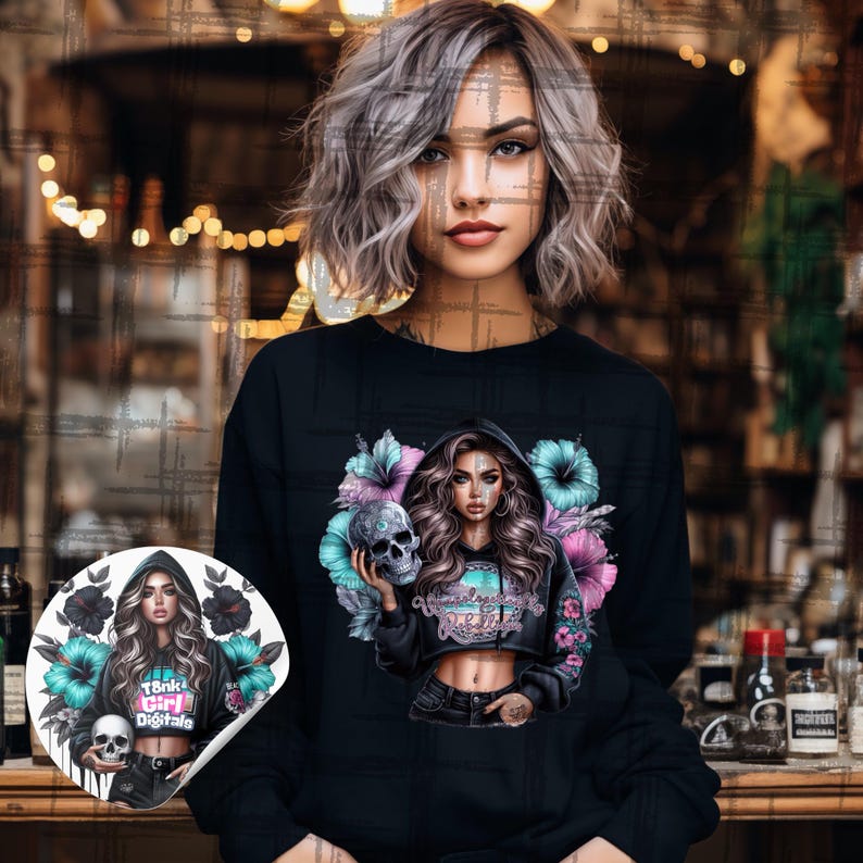 Pu&ograve; includere: Felpa nera con una grafica di una donna che tiene un teschio, circondata da fiori. Il design include il testo "Tank Girl Digitale". &Egrave; visibile anche un adesivo con lo stesso design. Lo sfondo &egrave; sfocato.