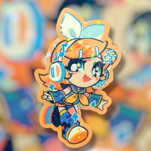 May include: A colorful sticker featuring a cartoon character with orange hair, blue headphones, and star accents. The character is wearing a blue and yellow outfit with musical notes and star details. The sticker has a holographic, glittery finish.