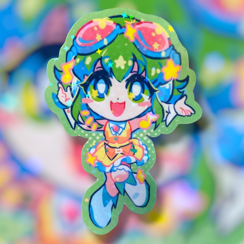 May include: A holographic sticker featuring a cartoon character with green hair, blue eyes, and a yellow dress. The character has star-shaped accents and is outlined in green. The sticker has a green border and a colorful background.