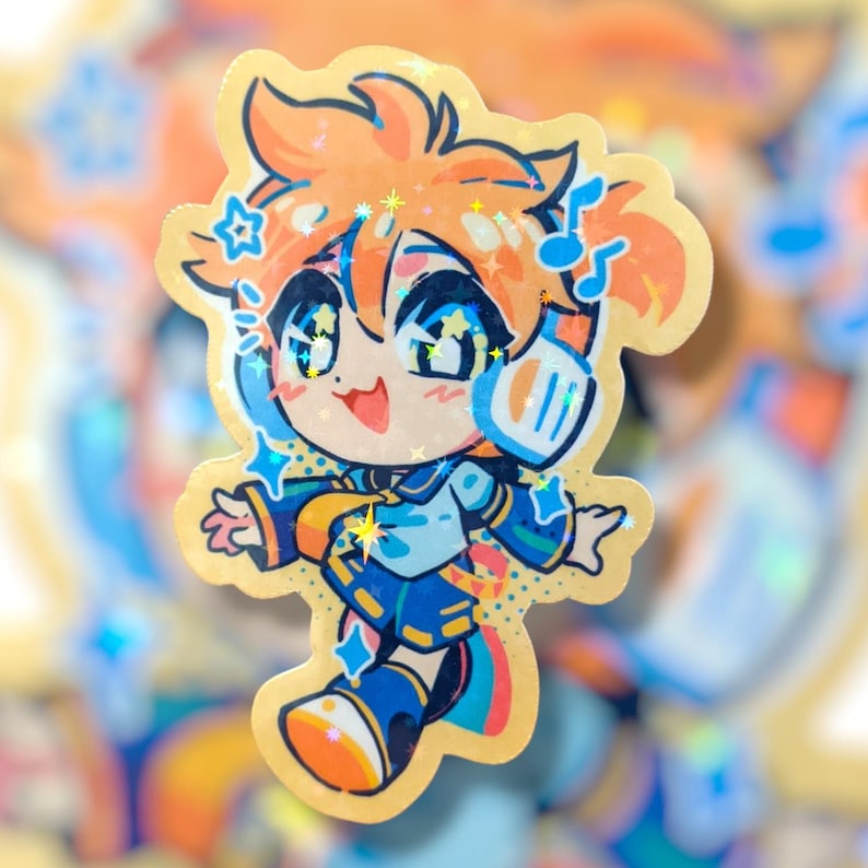 May include: A holographic sticker featuring a cartoon character with orange hair, blue eyes, and headphones. The character is wearing a blue and white outfit with star and music note accents. The sticker has a gold border and sparkling details.