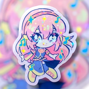 May include: Holographic sticker featuring a cute anime-style character with pink hair, blue eyes, and a blue and yellow outfit. The sticker has musical notes and star accents. The overall design is colorful and vibrant, with a glossy finish.