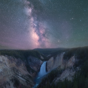 May include: A nighttime landscape featuring a waterfall cascading into a river, framed by a canyon and lush forest. The sky is filled with a vibrant display of the Milky Way and countless stars, creating a stunning celestial panorama.