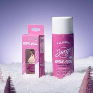 May include: A pink car air freshener spray and a box with a car air freshener. The spray can has a white top and the words "CARFUME Surge Winter Angel" with "Bubblegum, Vanilla & Cotton Candy" on the label. The box says "Winter Angel".