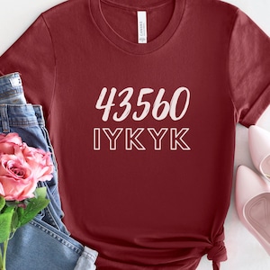 以下が含まれることがあります： 白文字で「43560 IYKYK」と書かれた、ワインレッドのTシャツです。