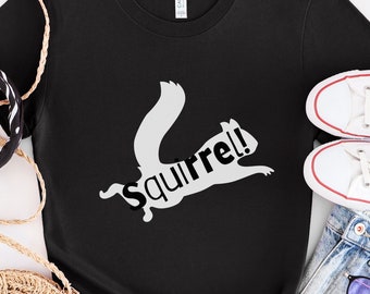 May include: Black t-shirt with a white silhouette of a squirrel jumping and the word "Squirrel!" written in white.