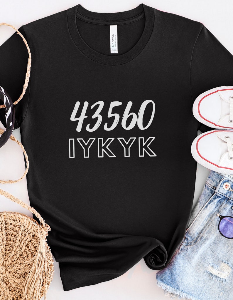 以下が含まれることがあります： 白い文字で「43560 IYKYK」と書かれた黒いTシャツ