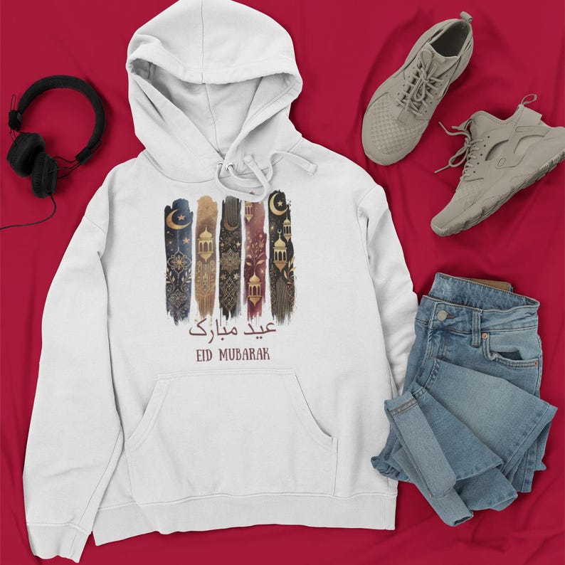 May include: White hooded sweatshirt featuring a graphic print of colourful Islamic art and the text "Eid Mubarak" in Arabic and English.