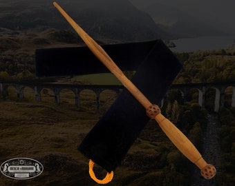May include: A wooden wand with a brown finish and intricate details. The wand has a knobby end and is displayed against a black velvet background.
