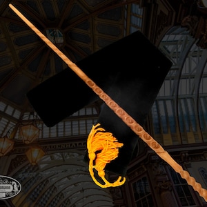 May include: A wooden wand with a twisted design and a gold tassel at the end. The wand is lying on a black fabric surface.
