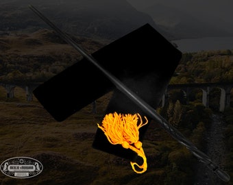 May include: A black wooden wand with a twisted design and a gold tassel. The wand is lying on a black velvet pouch with a gold tassel.