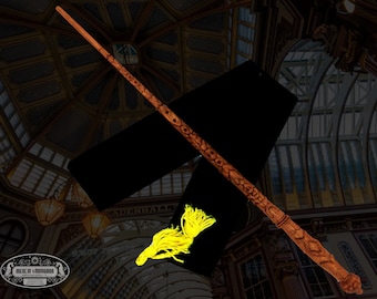 Op de afbeelding: Een houten toverstaf met ingewikkelde houtsnijwerk, met een bruin en gouden kleurenschema. De toverstaf wordt weergegeven tegen een zwarte achtergrond met een gele kwast.