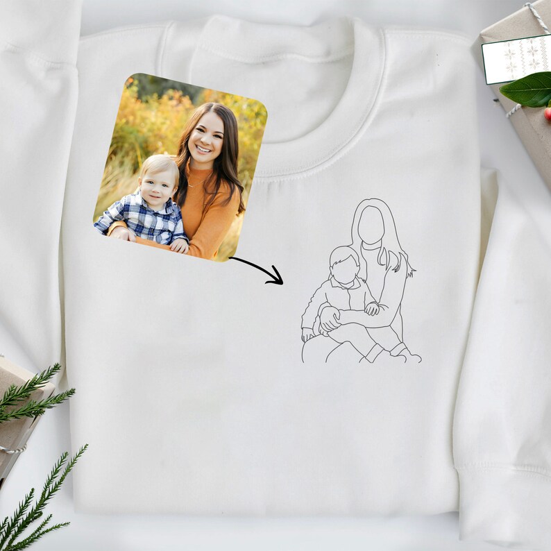 May include: A white sweatshirt with a photo of a mother and child in a fall setting. Below the photo is a line drawing of a mother and child.