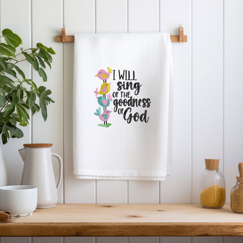 May include: White kitchen towel with a colorful embroidered design of birds and the text "I will sing of the goodness of God".