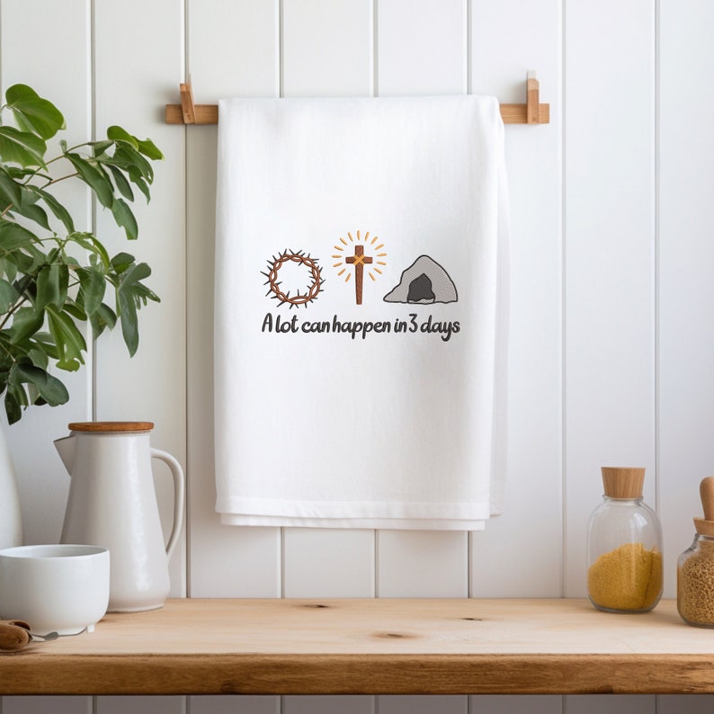 May include: White kitchen towel with a brown cross, a crown of thorns, and a stone tomb. The text "A lot can happen in 3 days" is printed below the images.
