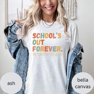 May include: Ash-colored long-sleeve t-shirt with the text "SCHOOL'S OUT FOREVER. RETIREMENT 2025" in orange, green, and yellow. The shirt is made of Bella Canvas material.
