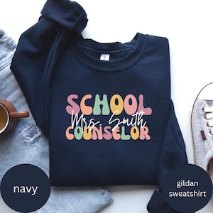 May include: Navy blue Gildan sweatshirt with the text "SCHOOL Mrs. Smith COUNSELOR" in colorful, retro-style lettering.