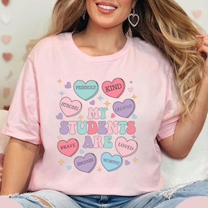 May include: Pink t-shirt with the text "My Students Are" surrounded by colorful hearts with words like "Friendly", "Kind", "Brave", "Creative", "Loved", "Worthy", and "Enough".