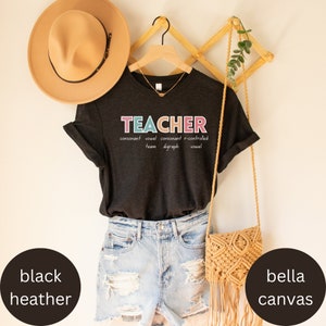 May include: A black heather grey t-shirt with the word "TEACHER" written in colorful letters. The word is defined as "consonant vowel consonant r-controlled team digraph vowel".