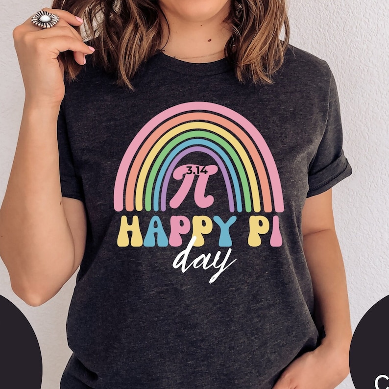 Może przedstawiać: Ciemnoszara koszulka z kolorowym wzorem tęczy i napisem "3.14 &pi; HAPPY PI day". Tęcza ma pastelowe kolory. Zabawna koszulka na obchody Dnia Liczby Pi.