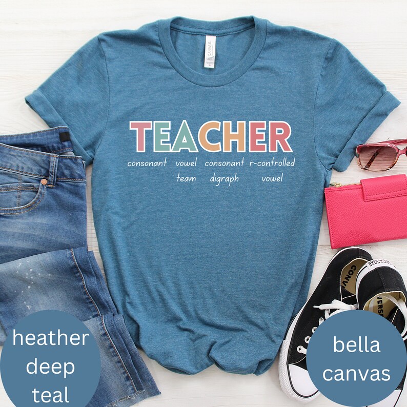 May include: A teal blue t-shirt with the word "TEACHER" in colorful letters. The word is broken down into its parts of speech, with the text "consonant vowel consonant r-controlled team digraph vowel" underneath.