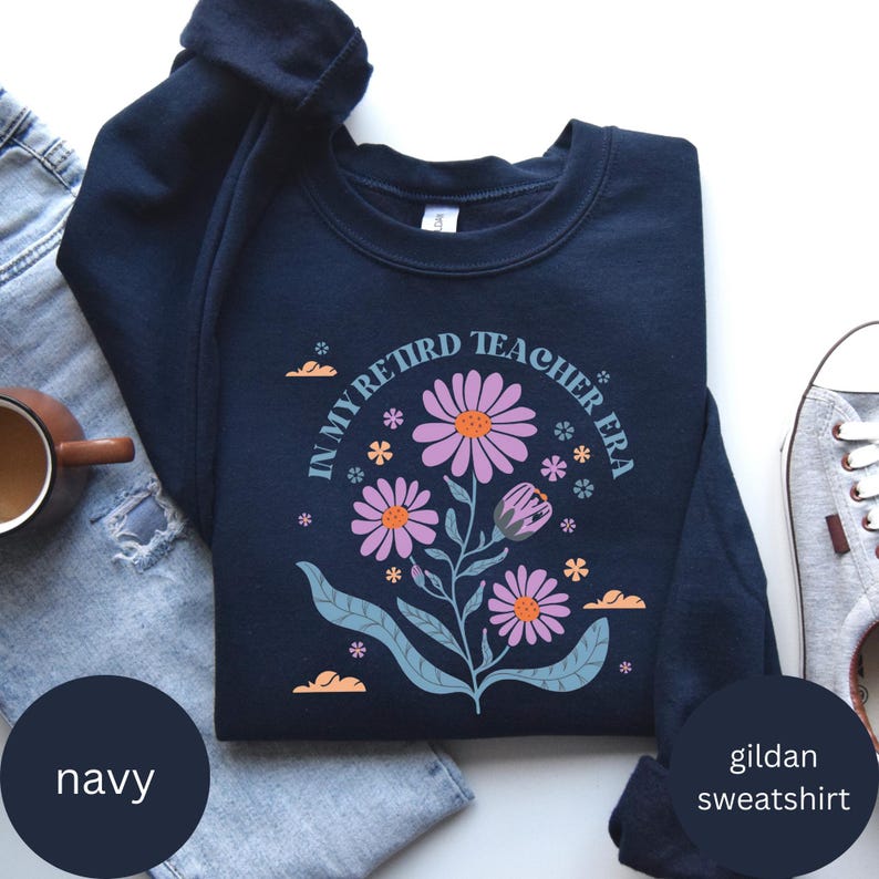 May include: Navy blue Gildan sweatshirt with a floral design and the text "In My Retired Teacher Era".