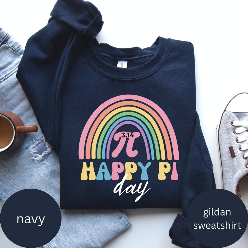 Może przedstawiać: Granatowa bluza Gildan z kolorowym wzorem tęczy i napisem "3.14 Happy Pi Day". Grafika zawiera symbol pi w stylu retro. Bluza jest złożona na białej powierzchni.