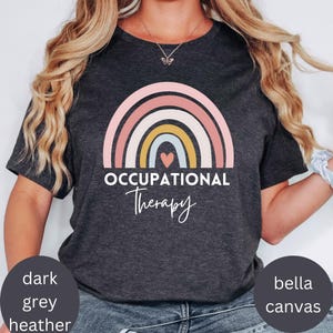 Könnte beinhalten: Ein dunkel-helles graues T-Shirt mit einem Regenbogen-Design und dem Text "Occupational Therapy".