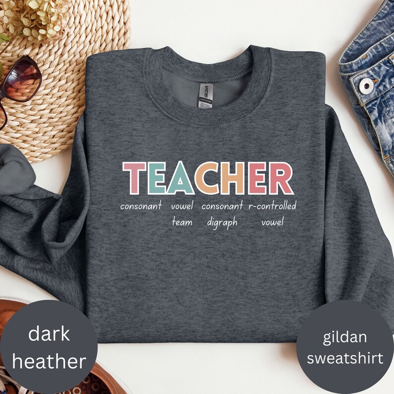 May include: Dark heather grey Gildan sweatshirt with the word "TEACHER" in colorful letters. The word is broken down into its parts of speech: consonant, vowel, consonant, r-controlled vowel, team, digraph.