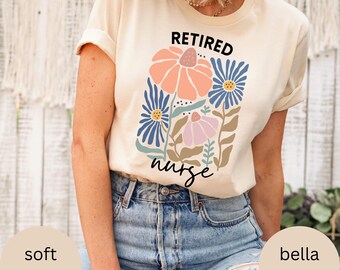 May include: A cream colored t-shirt with the text "Retired nurse" and a floral design in shades of blue, pink, and orange.