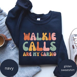Peut inclure: Sweat-shirt bleu marine Gildan avec le texte "Walkie Calls Are My Cardio" en police rétro colorée.